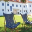 Zwei Sonnenstühle stehen im Schatten eines Baumes auf der Wiese vor Schloss Negova